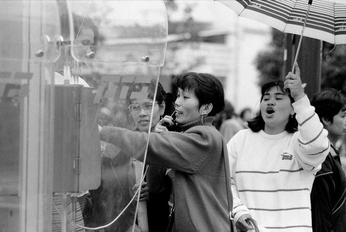 An einer oeffentlichen Telefonzelle telefonieren philippinische Gastarbeiterinnen ihren Familien in den Philippinen, die sie oft jahrelang nicht sehen.<br>(Dezember 1998)