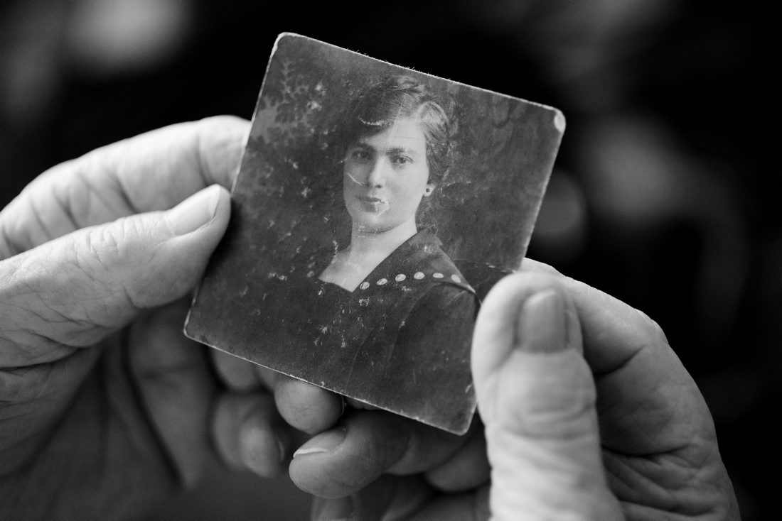 Die Tochter haelt ein Bild ihrer im Holocaust umgebrachten Mutter in den Händen.